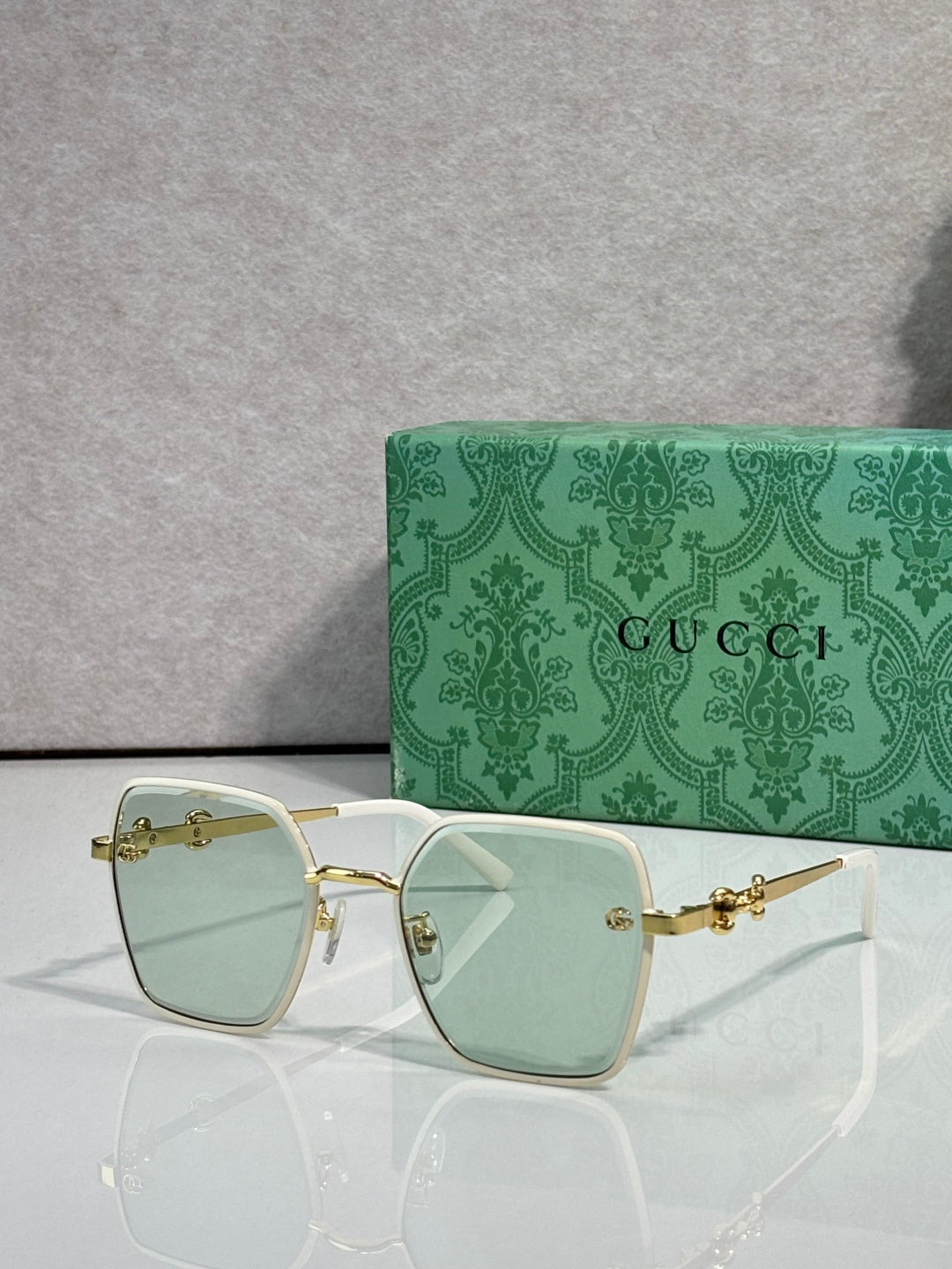 Gucci sunglasses with white frames and light green gradient lenses, square corners.