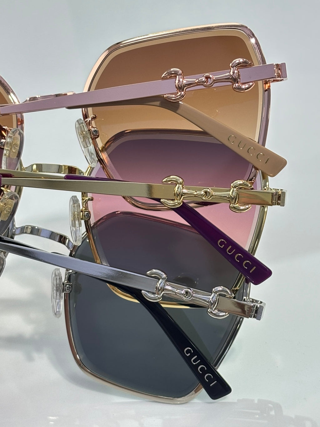 Gucci sunglasses close-up showing stacked gold frames with pink and purple lenses.