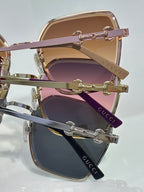 Gucci sunglasses close-up showing stacked gold frames with pink and purple lenses.