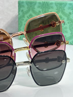 Gucci sunglasses multiple styles stacked: gold frames, dark lenses, pink-tinted lenses.