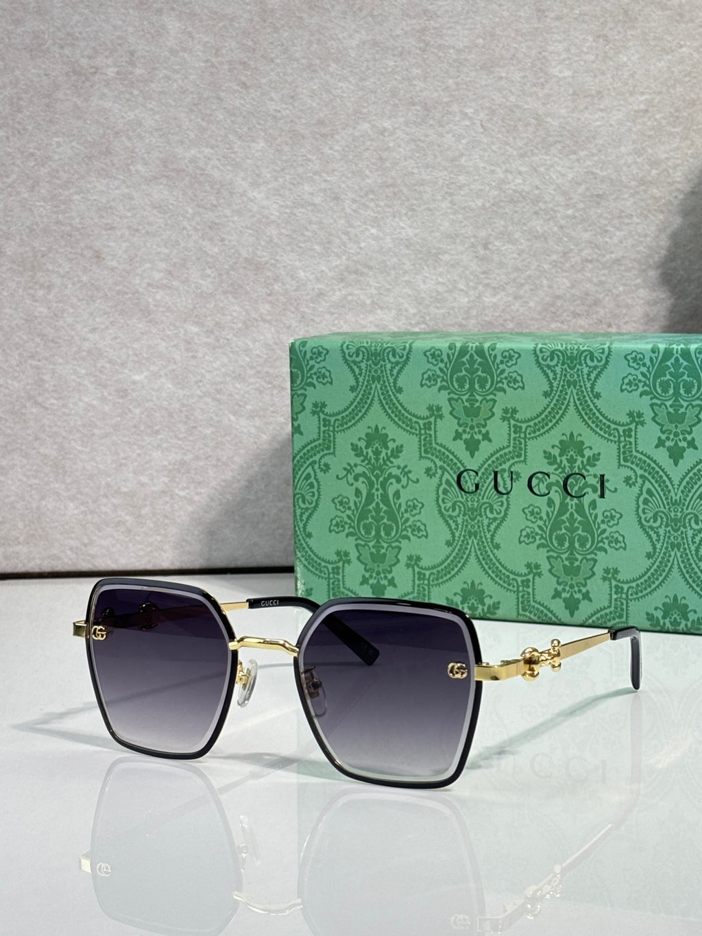 Gucci sunglasses with dark blue frames and purple gradient lenses, square corners.