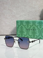 Gucci sunglasses with dark blue frames and purple gradient lenses, square corners.