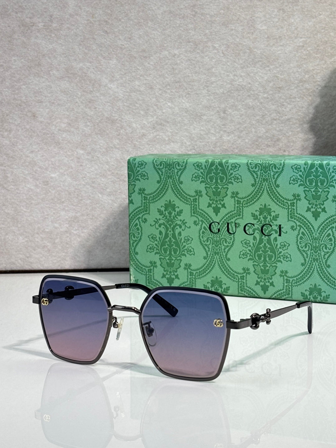 Gucci sunglasses with dark blue frames and purple gradient lenses, square corners.