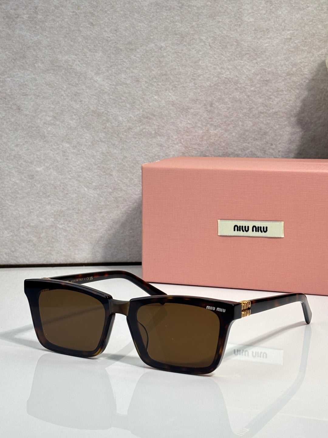 Rectangular sunglasses with black frame and brown-tinted lenses, miu miu logo