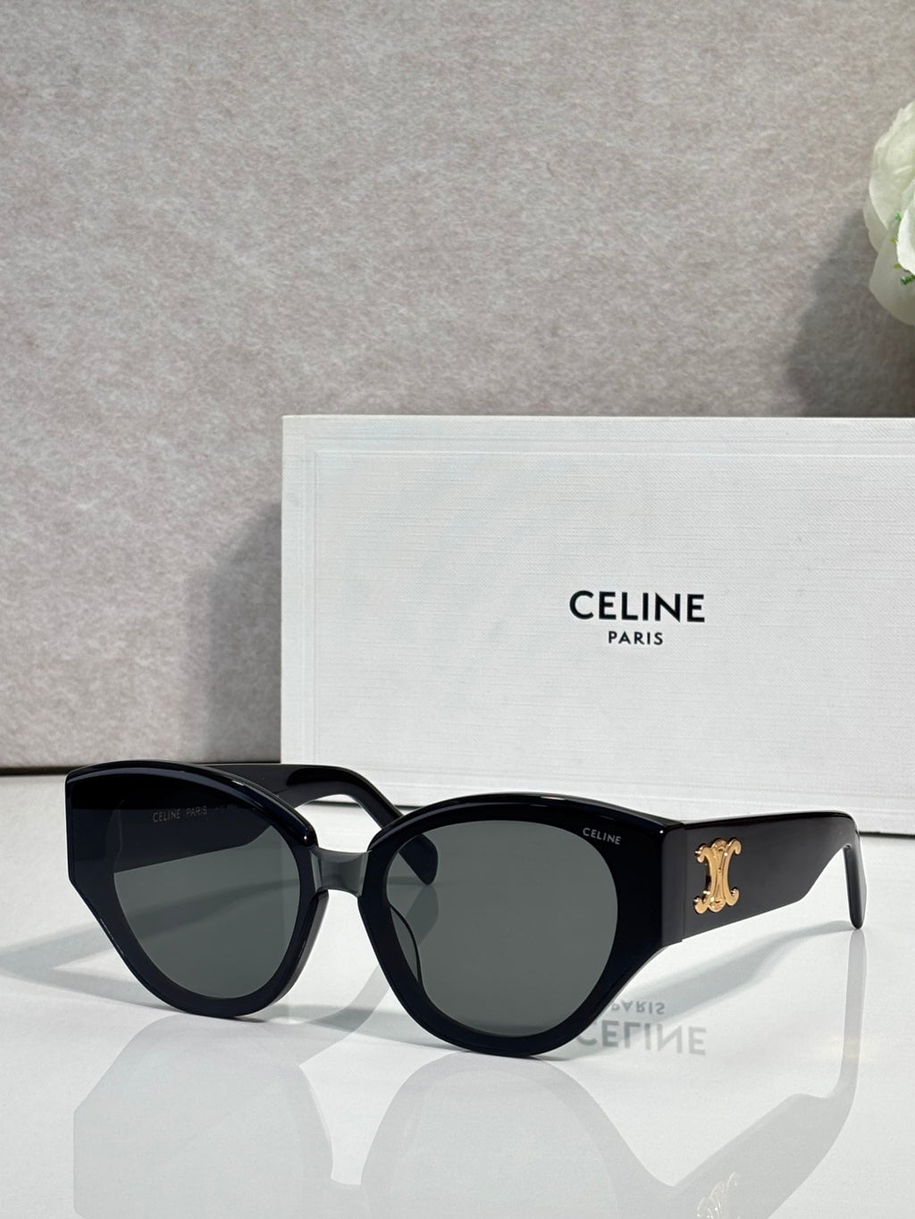 Celine sunglasses with glossy black frames and dark smoke lenses, gold logo on temple.