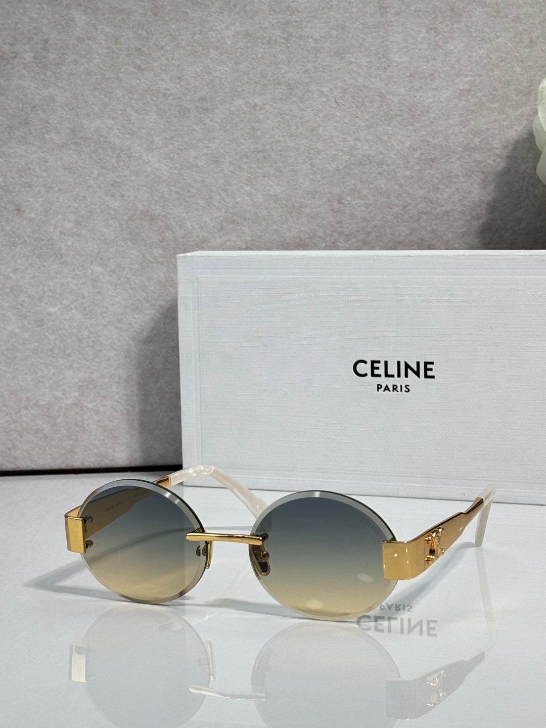 Celine sunglasses with round blue-tinted lenses and gold-tone frame, curved temple arms