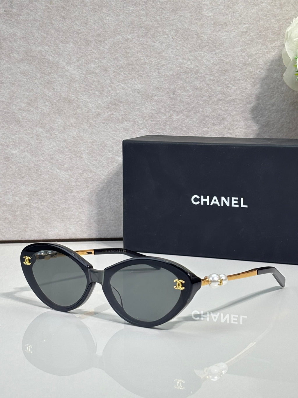 Chanel sunglasses with dark green lenses and black frames, gold-tone logo detail