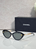 Chanel sunglasses with dark green lenses and black frames, gold-tone logo detail