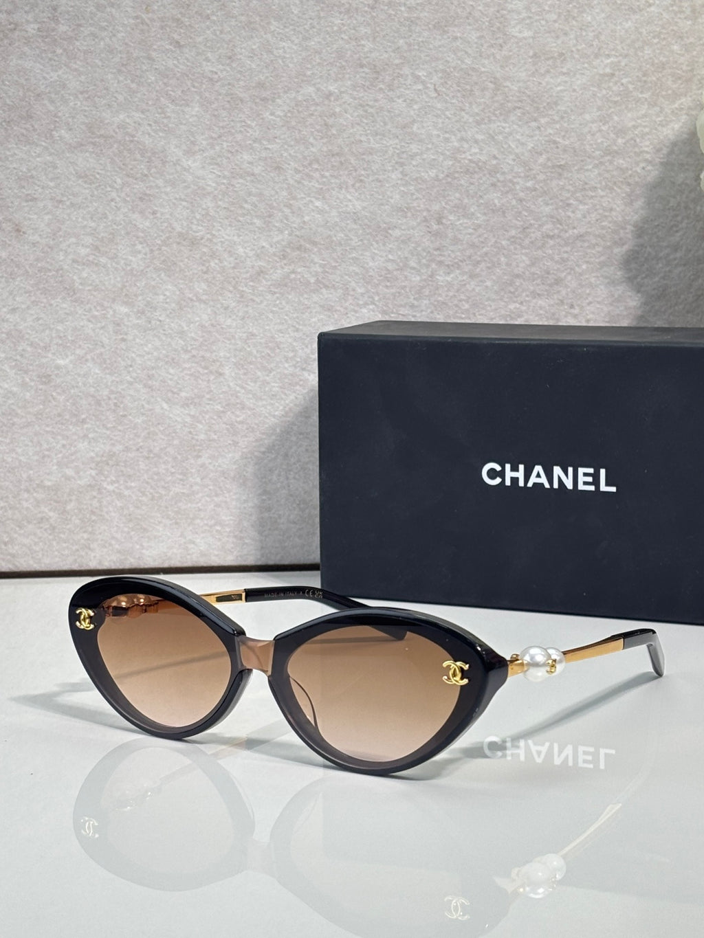 Chanel sunglasses with beige lenses and black frames, gold-tone logo detail