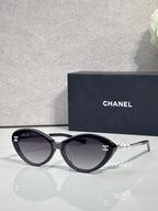 Chanel sunglasses with dark brown lenses and black frames, gold-tone logo and pearl detail
