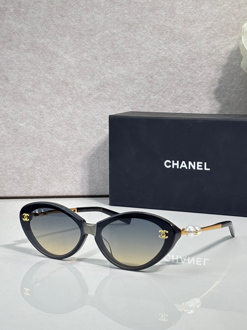 Chanel sunglasses with light brown lenses and black frames, gold-tone logo detail