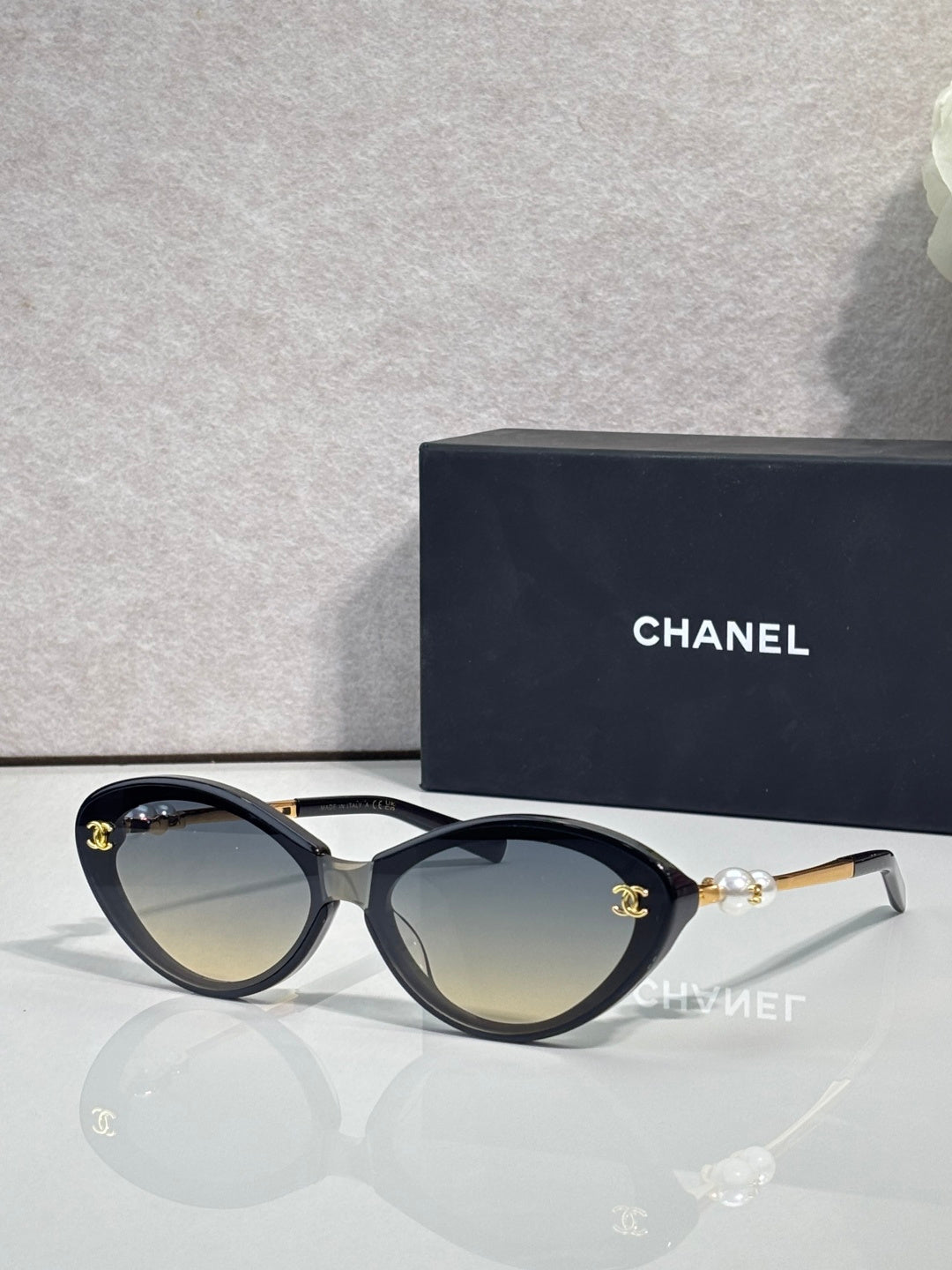 Chanel sunglasses with light brown lenses and black frames, gold-tone logo detail