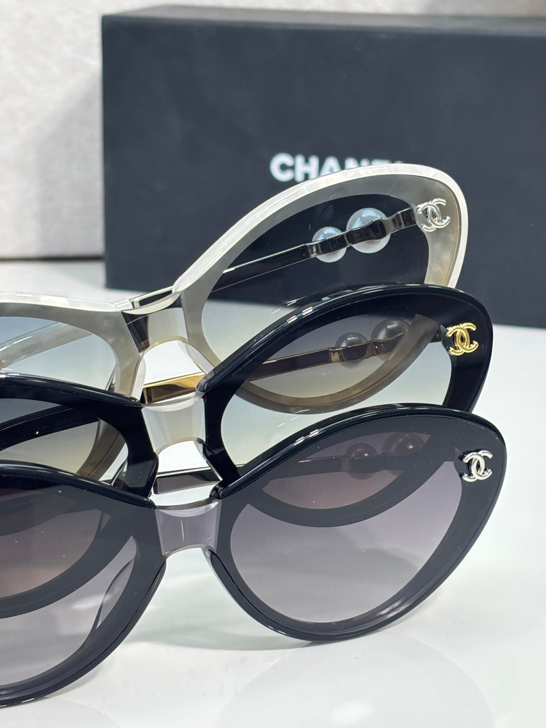 Chanel sunglasses close-up: white and black oval frames with lenses and gold logos