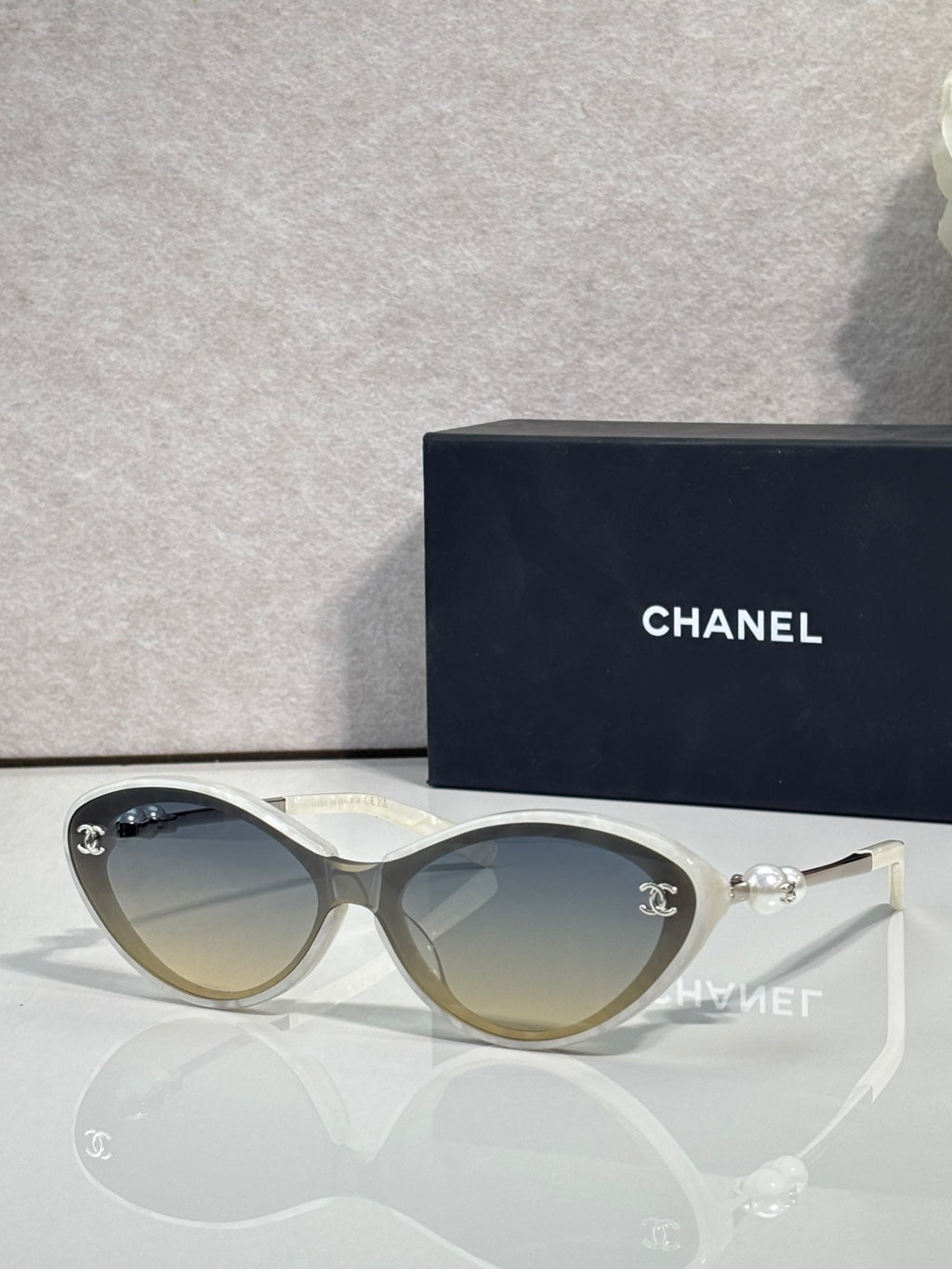 Chanel sunglasses with gold-tinted lenses and light frames, pearl and gold-tone detail