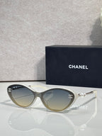 Chanel sunglasses with gold-tinted lenses and light frames, pearl and gold-tone detail