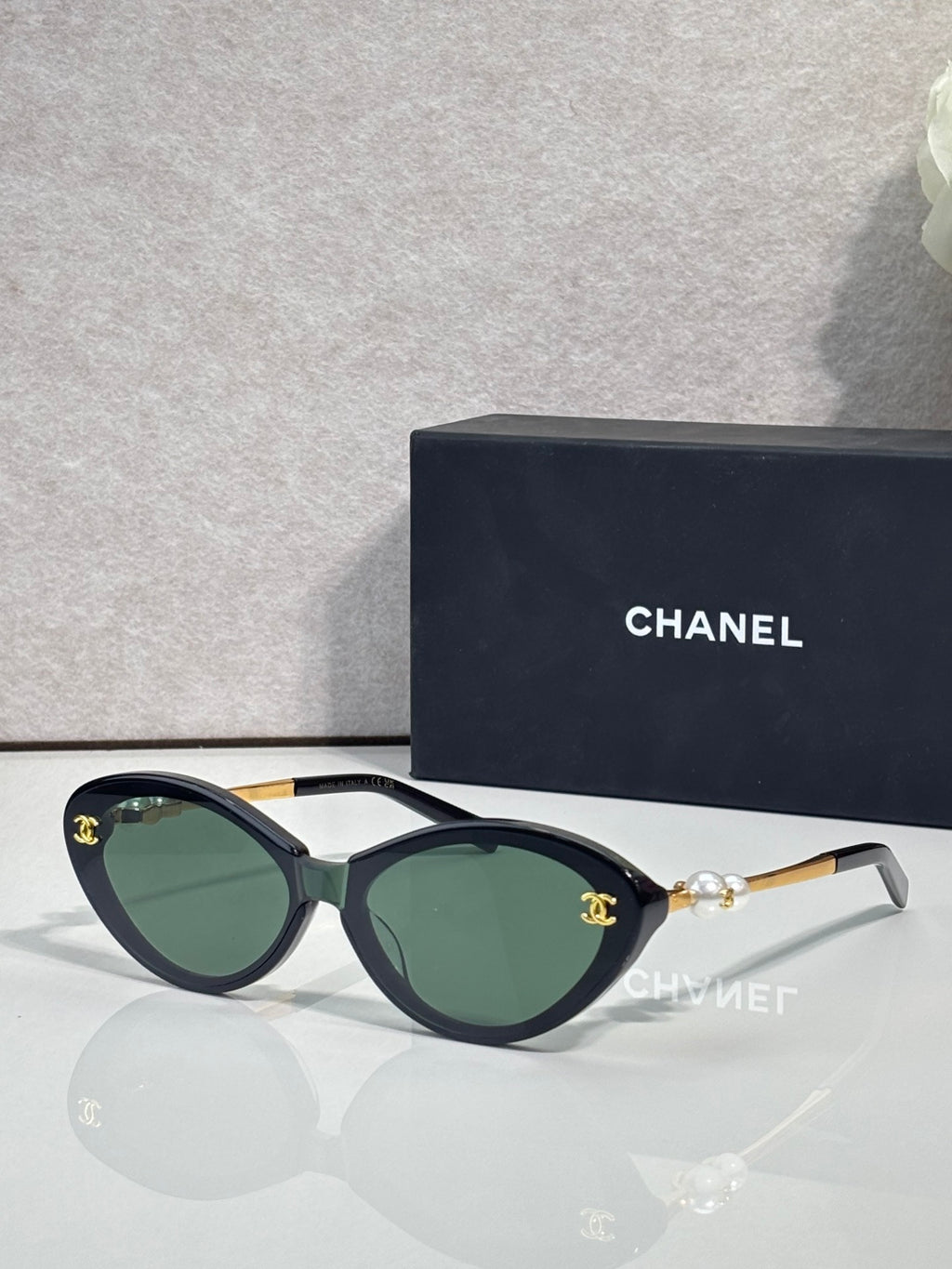 Chanel sunglasses with dark green lenses and black frames, gold-tone temple detail