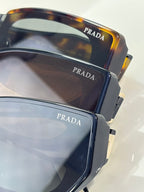 Prada sunglasses close-up showing dark and tortoise frames with temple branding