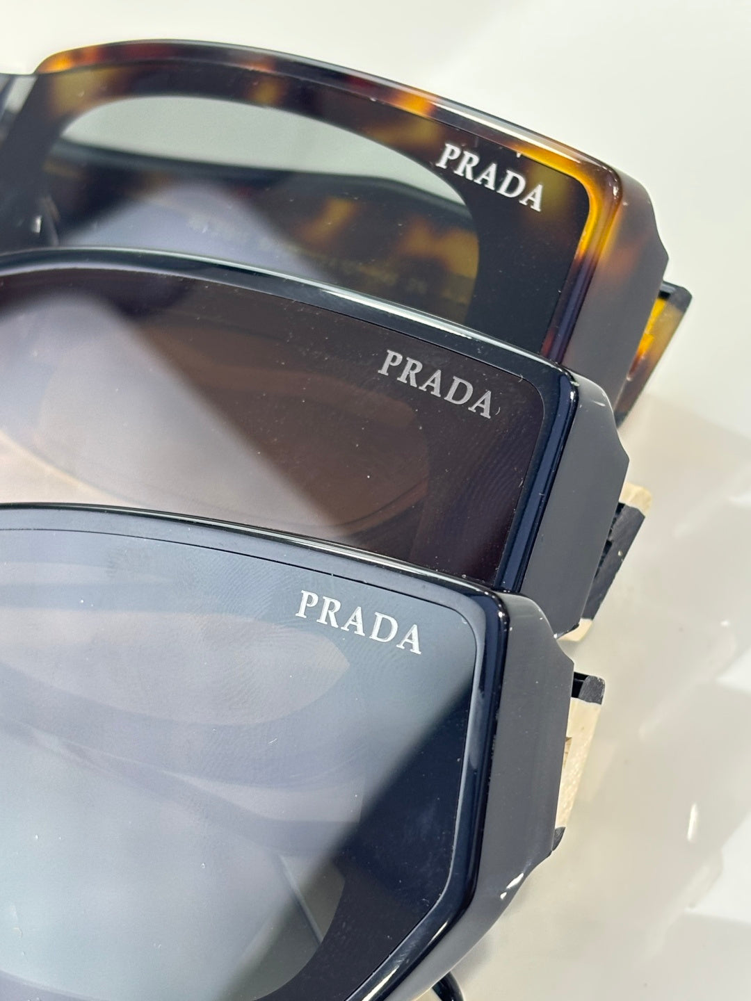 Prada sunglasses close-up showing dark and tortoise frames with temple branding