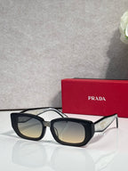 Prada sunglasses with black frame and amber-tinted lenses, oversized cat-eye style