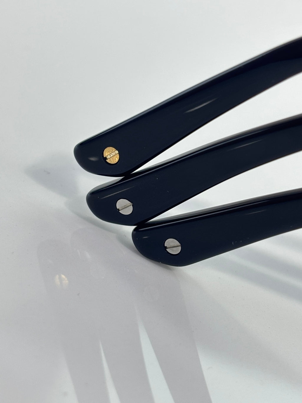 Navy eyeglass temple tips with metal logo accents and rounded cutouts