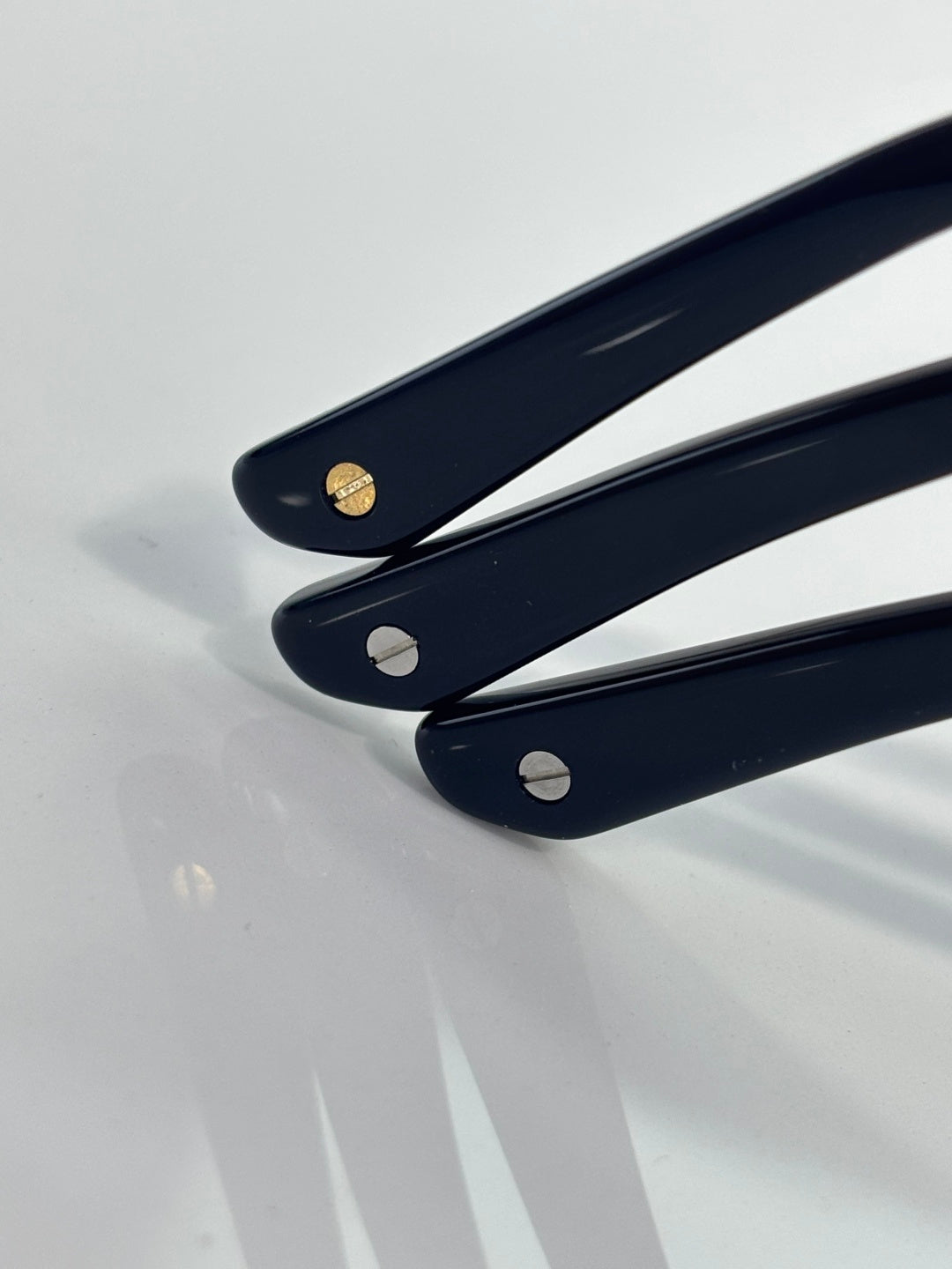 Navy eyeglass temple tips with metal logo accents and rounded cutouts