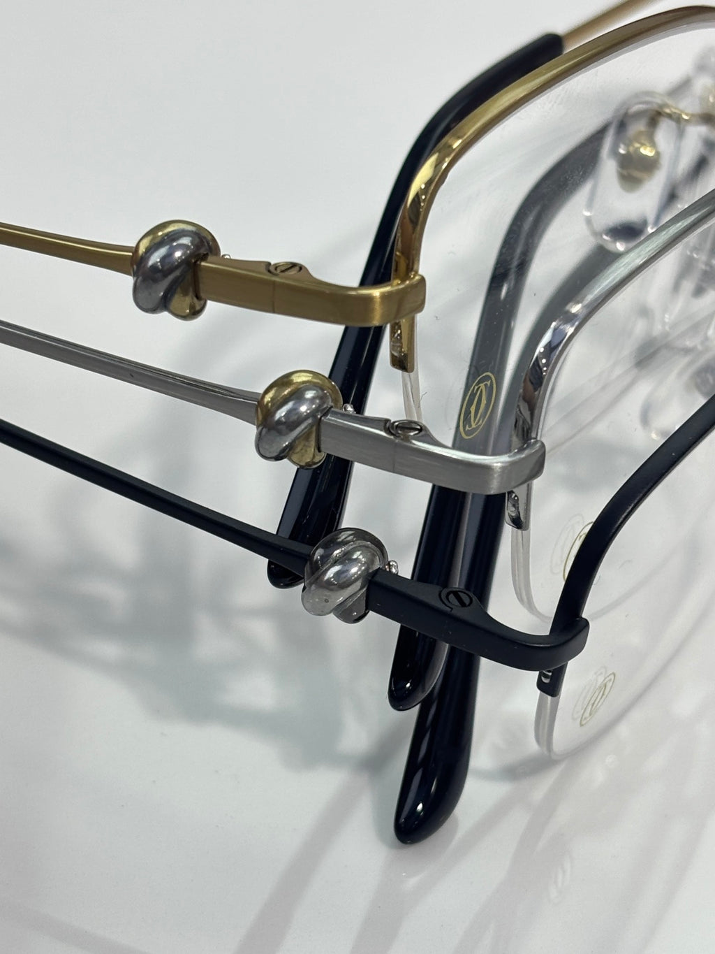 Cartier glasses close-up: dark arms with gold hinge hardware and clear lenses