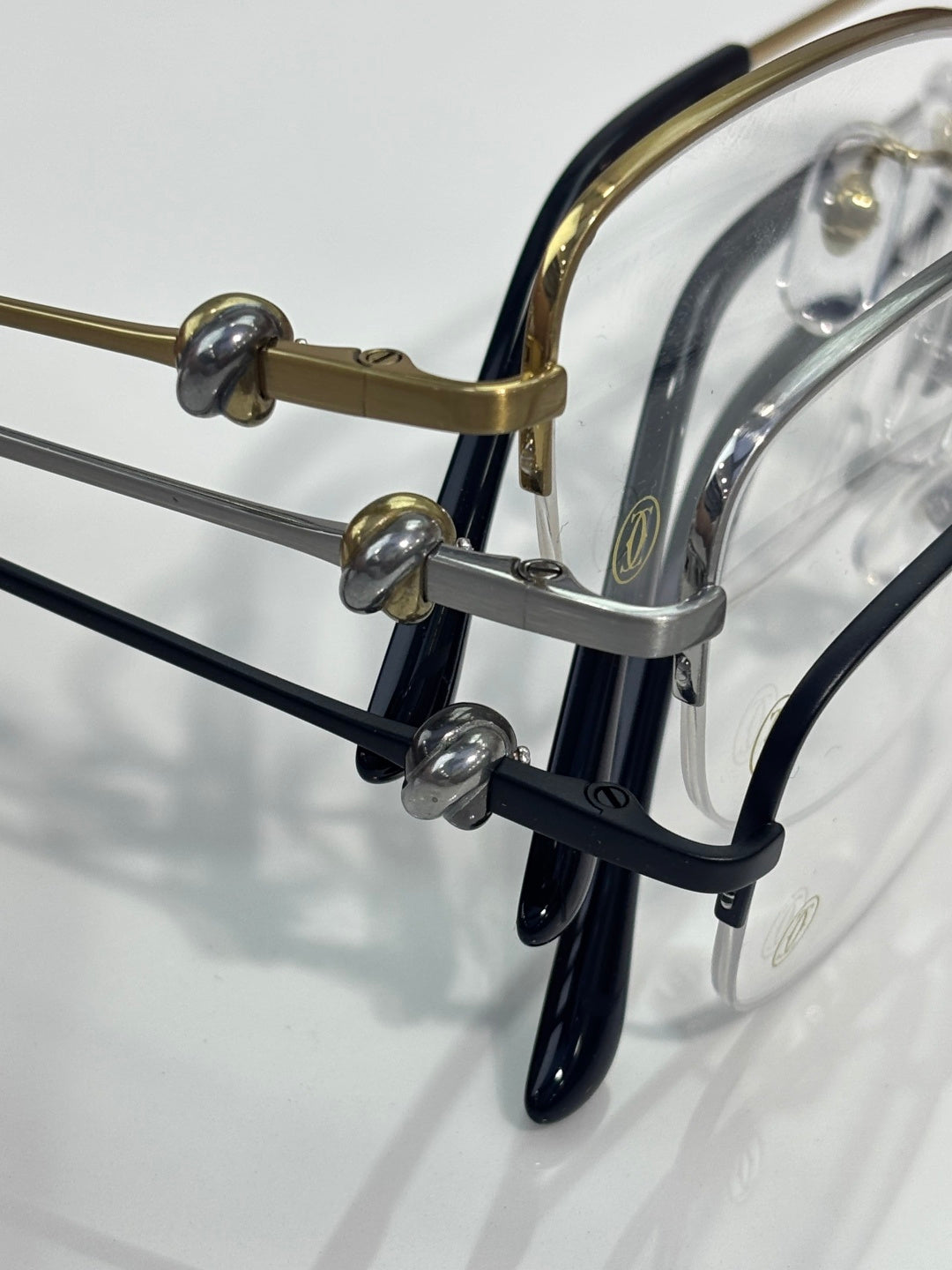 Cartier glasses close-up: dark arms with gold hinge hardware and clear lenses