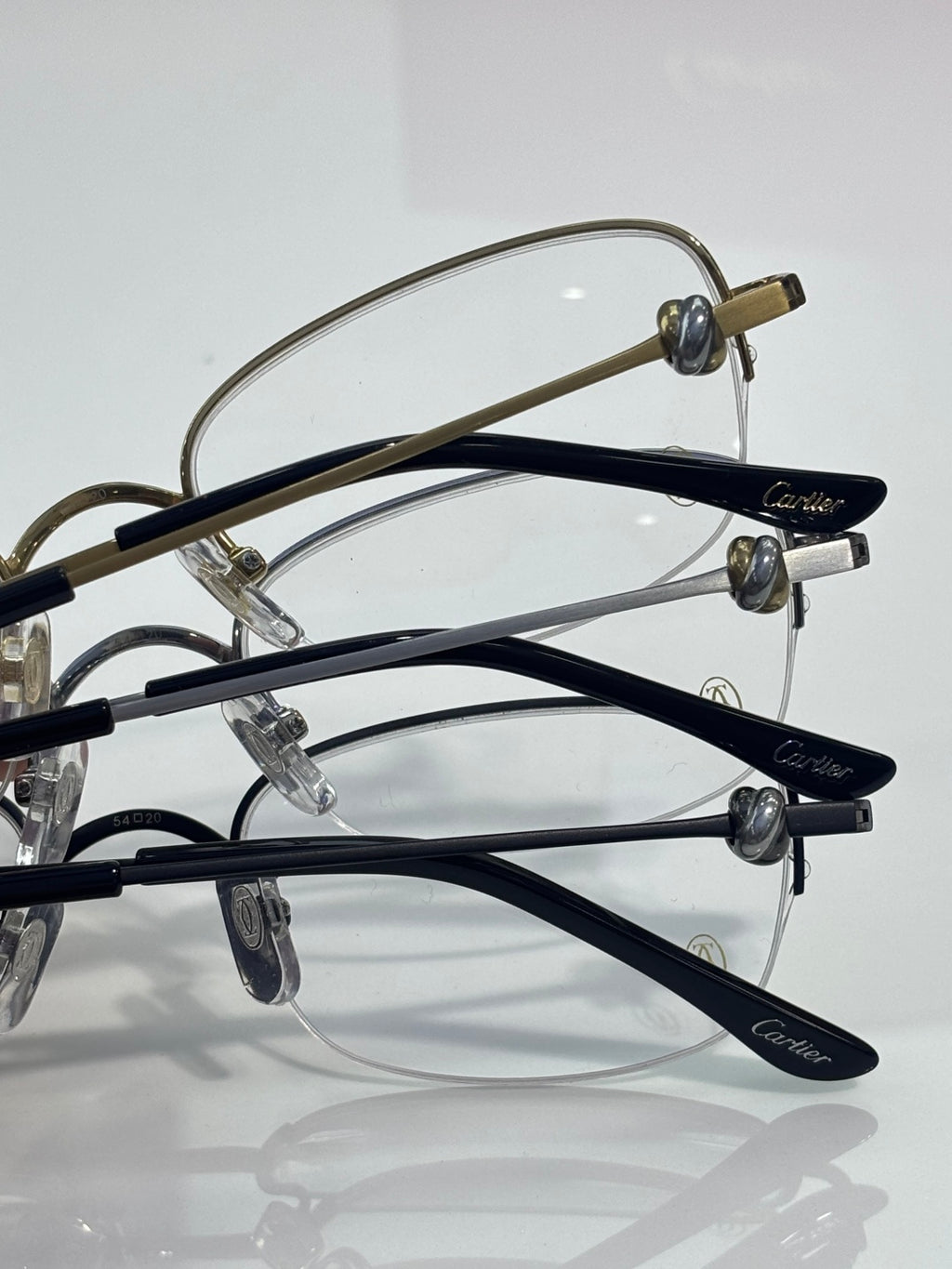 Cartier glasses close-up: multiple dark and gold temple frames with clear lenses
