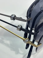 Sunglasses hinge detail with dark arms, gold accents, and round tinted lens frame