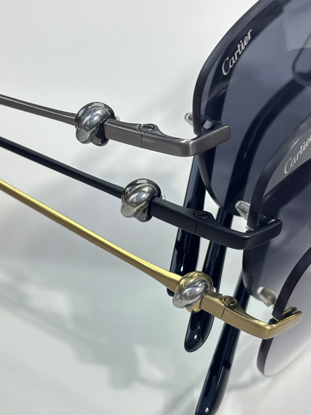 Sunglasses hinge detail with dark arms, gold accents, and round tinted lens frame