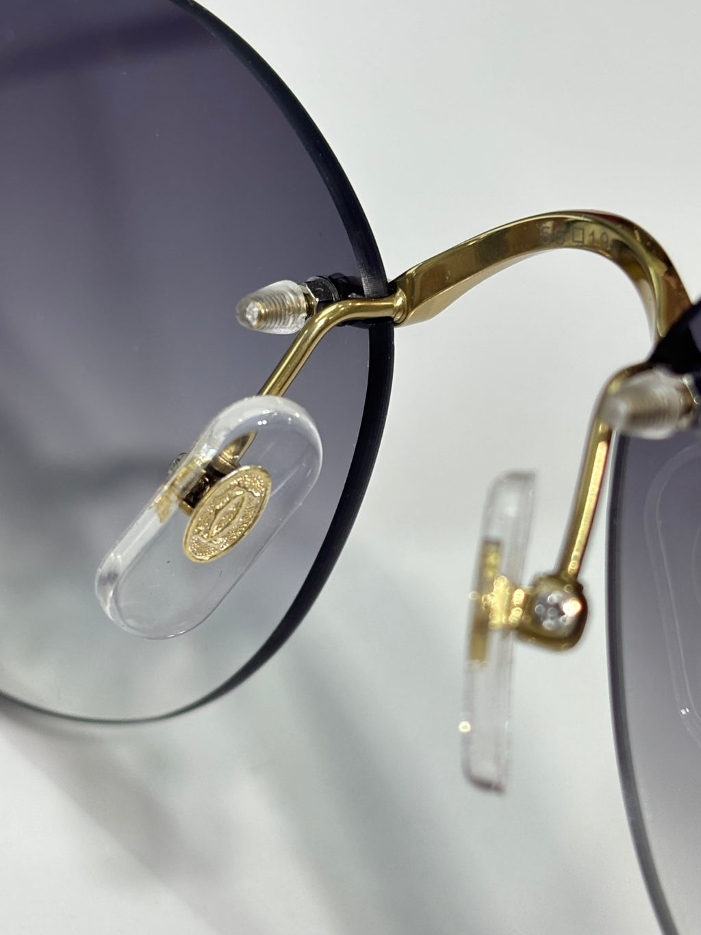 Gold eyeglasses detail: round clear lens and gold metal temple with hinge
