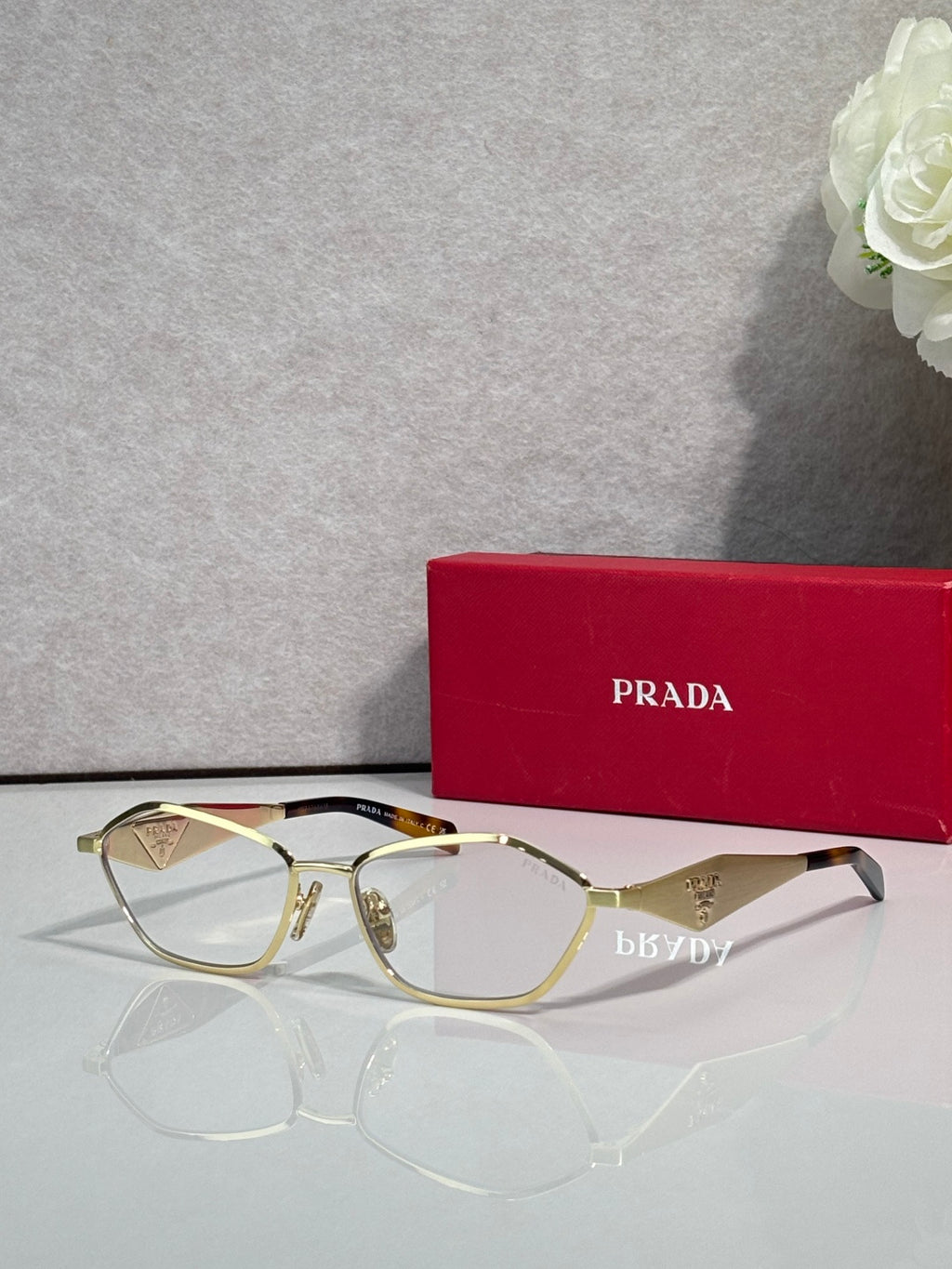 Prada optical glasses, gold metal frame, clear lenses, angled front