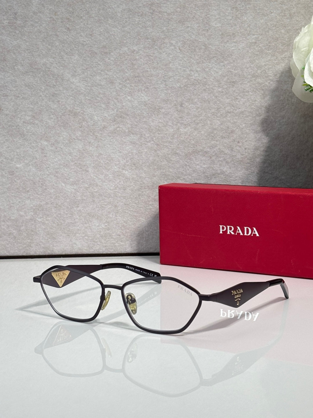 Prada optical glasses, dark frame with gold accents, clear lenses, side view