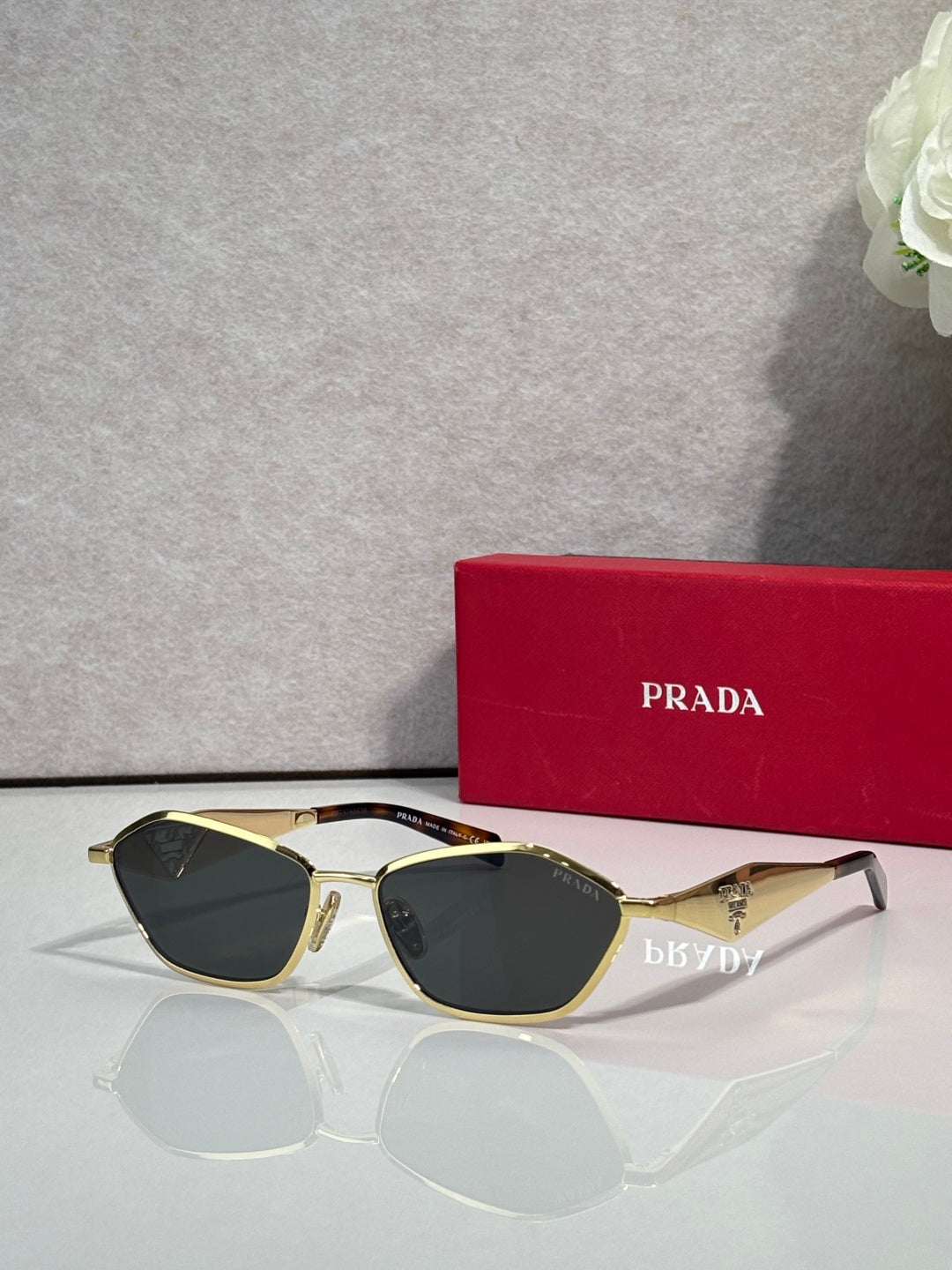 Prada cat-eye sunglasses with gold frame and dark lenses, PRADA logo on arms