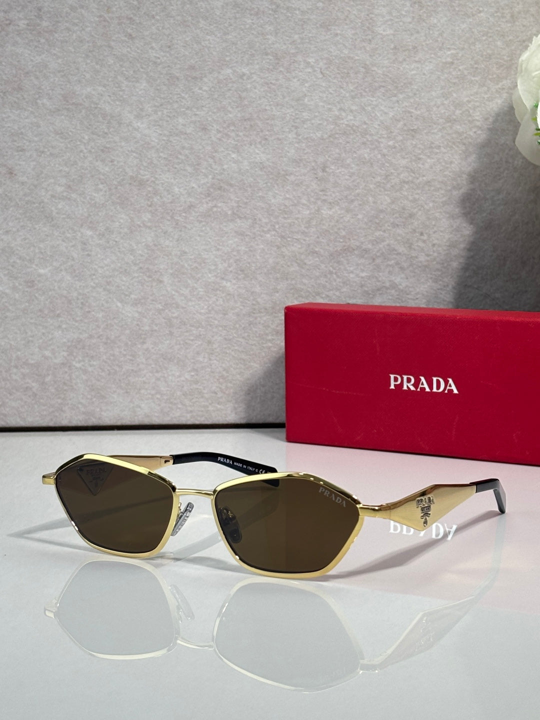 Prada cat-eye sunglasses with gold frame and dark olive lenses, PRADA logo on arms