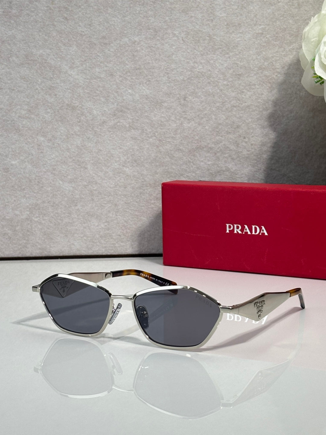 Prada cat-eye sunglasses with metallic frame and dark lenses, PRADA logo on arms