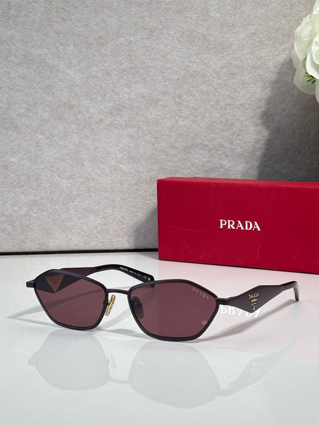 Prada cat-eye sunglasses with gold-and-black frame and burgundy lenses, PRADA logo