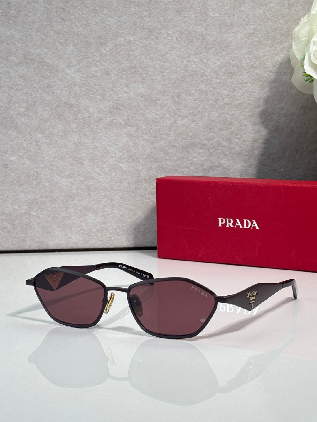 Prada cat-eye sunglasses with gold-and-black frame and burgundy lenses, PRADA logo