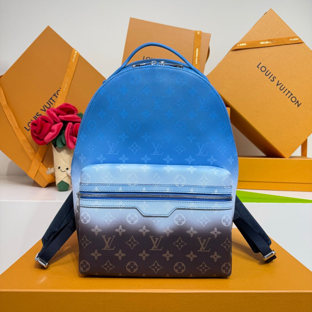 Blue monogram backpack with top handle, front zip pocket, and shoulder straps