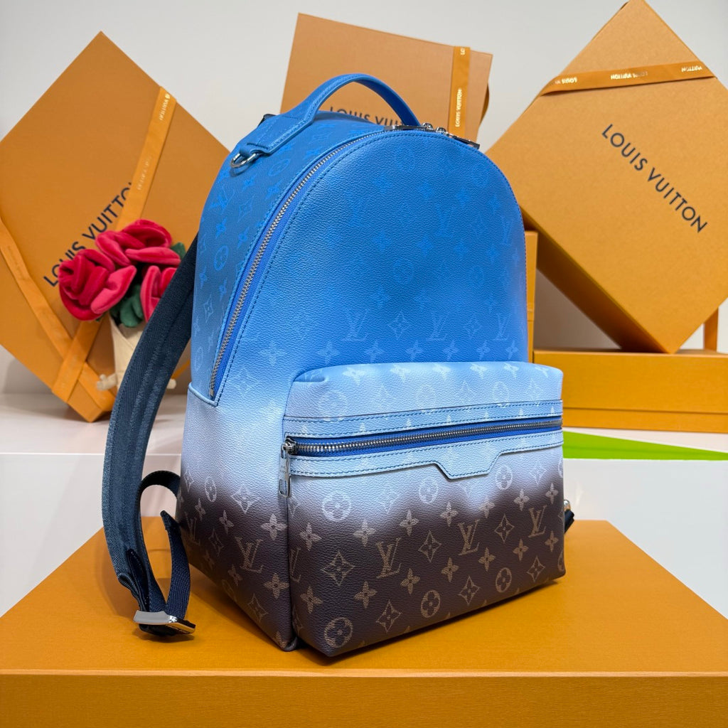 Blue monogram backpack with curved top handle, front zip pocket, and webbing strap