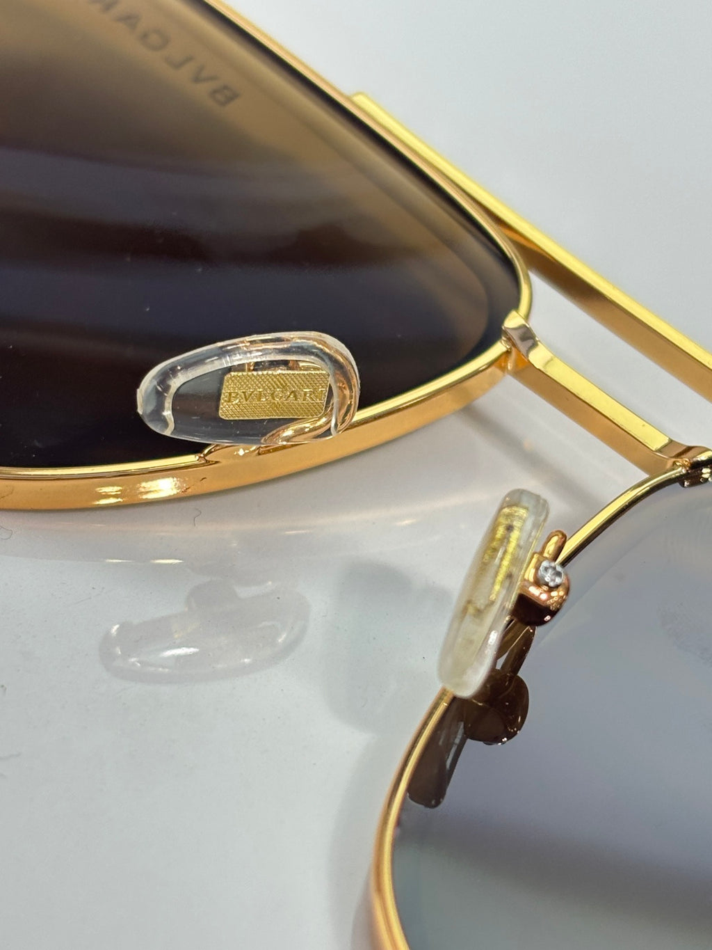 Gold-tone sunglasses close-up of hinge and bridge with dark lens tint