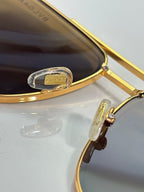 Gold-tone sunglasses close-up of hinge and bridge with dark lens tint