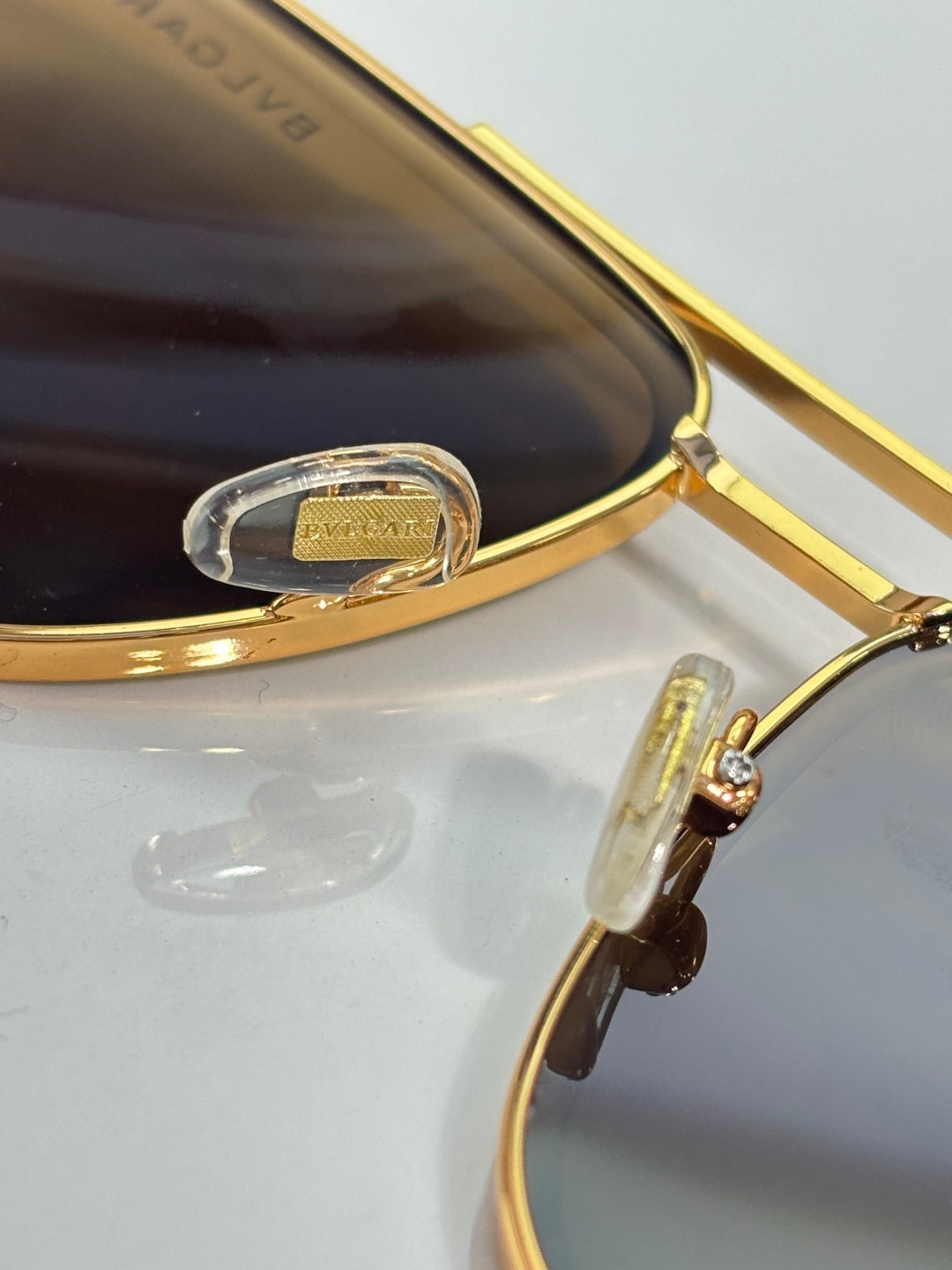 Gold-tone sunglasses close-up of hinge and bridge with dark lens tint