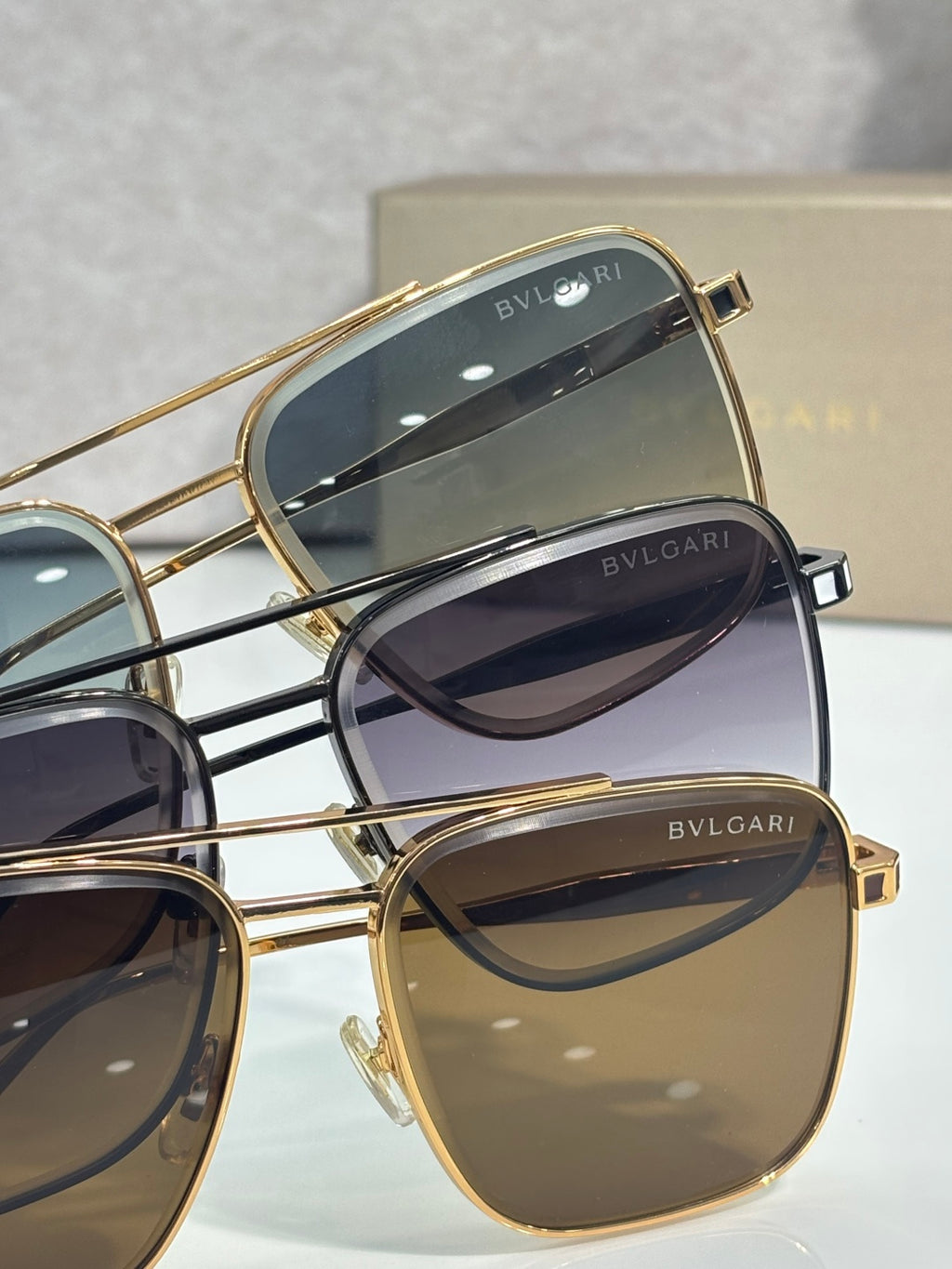 Gold-tone sunglasses close-up showing lens tints and BVLGARI logo on frames