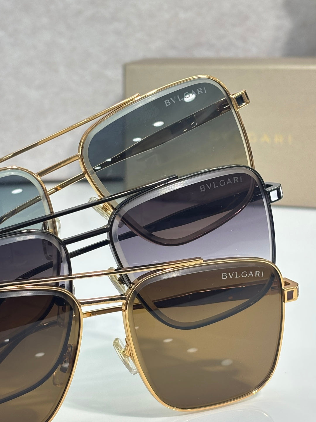 Gold-tone sunglasses close-up showing lens tints and BVLGARI logo on frames