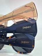 YSL sunglasses in case: nude-gold frame and dark lenses beside navy frame