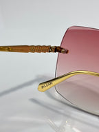 Gold sunglasses with pink lenses and engraved temple bridge detail