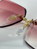 Gold metal sunglasses with purple-pink lenses, close-up of temple detail