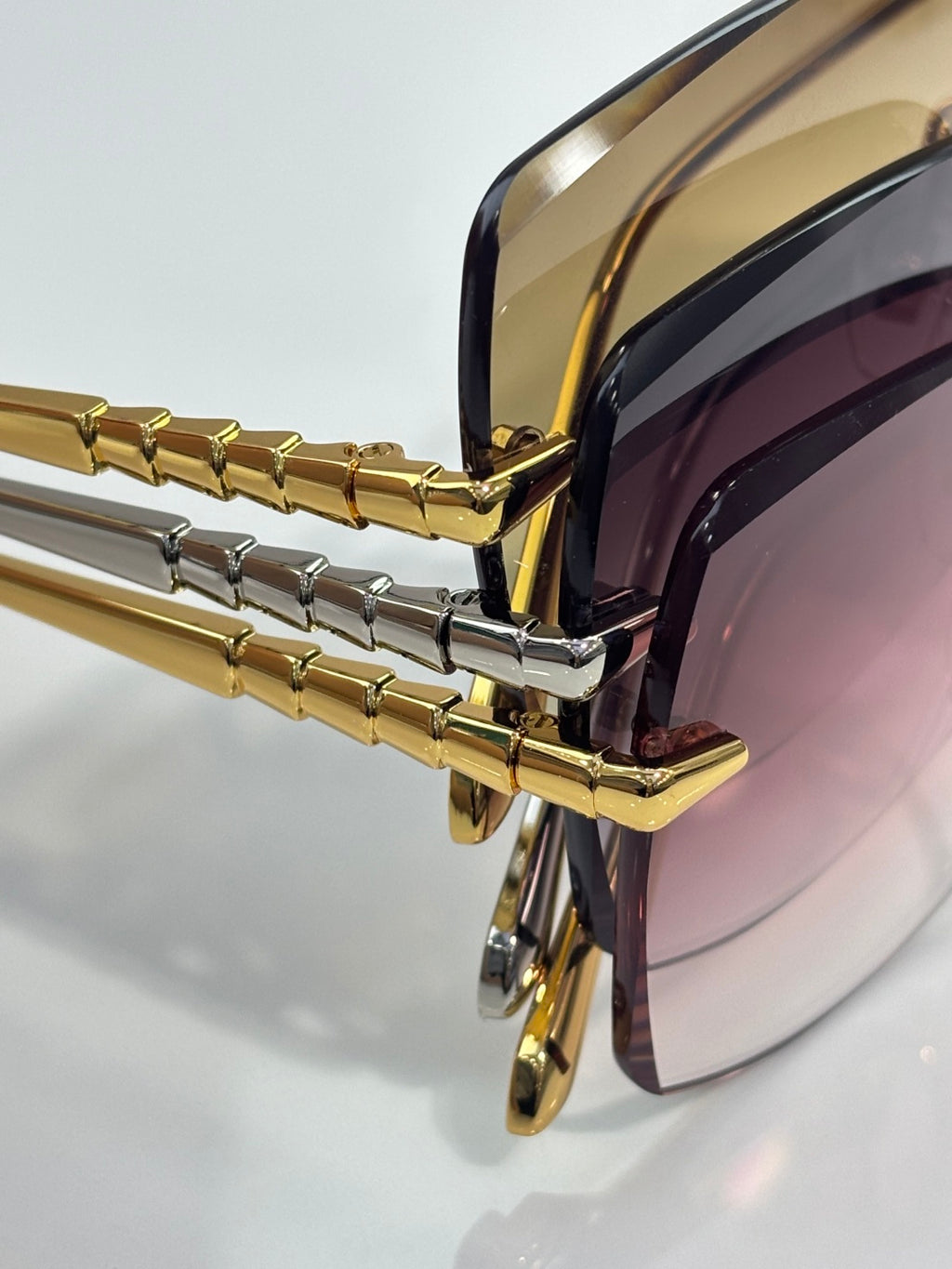 Gold sunglasses with dark lenses, close-up of side hinges and temple design