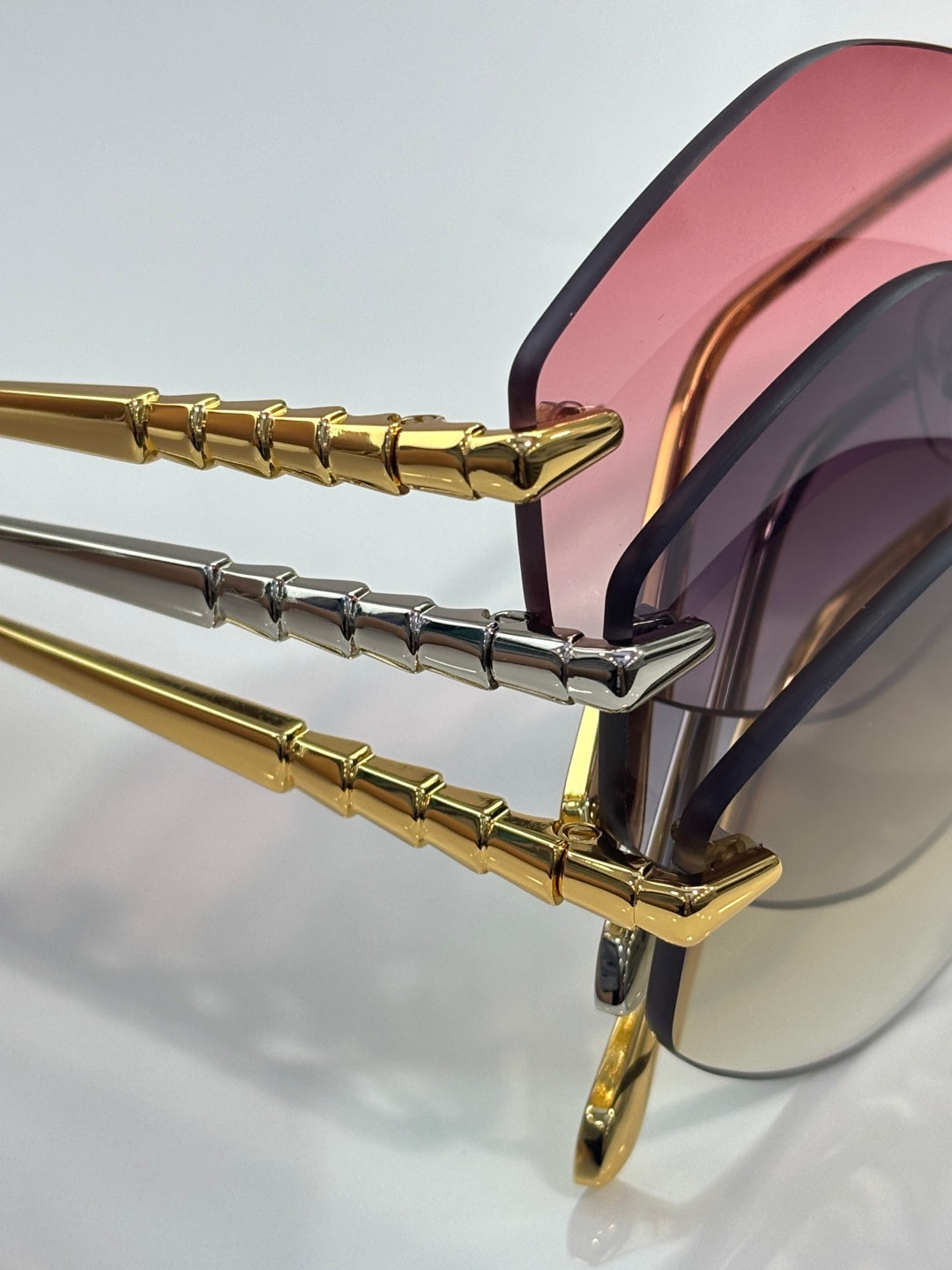 Bvlgari sunglasses close-up: gold frame with pink lens and black temple detail